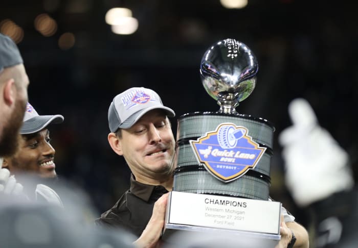 Western Michigan celebrating a Quick Lane Bowl victory with the trophy.